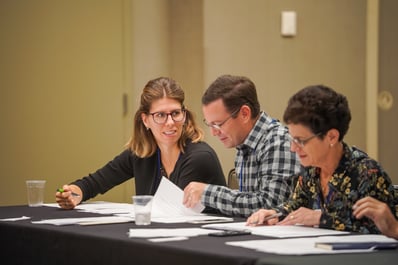 Conference attendees talk while reading papers